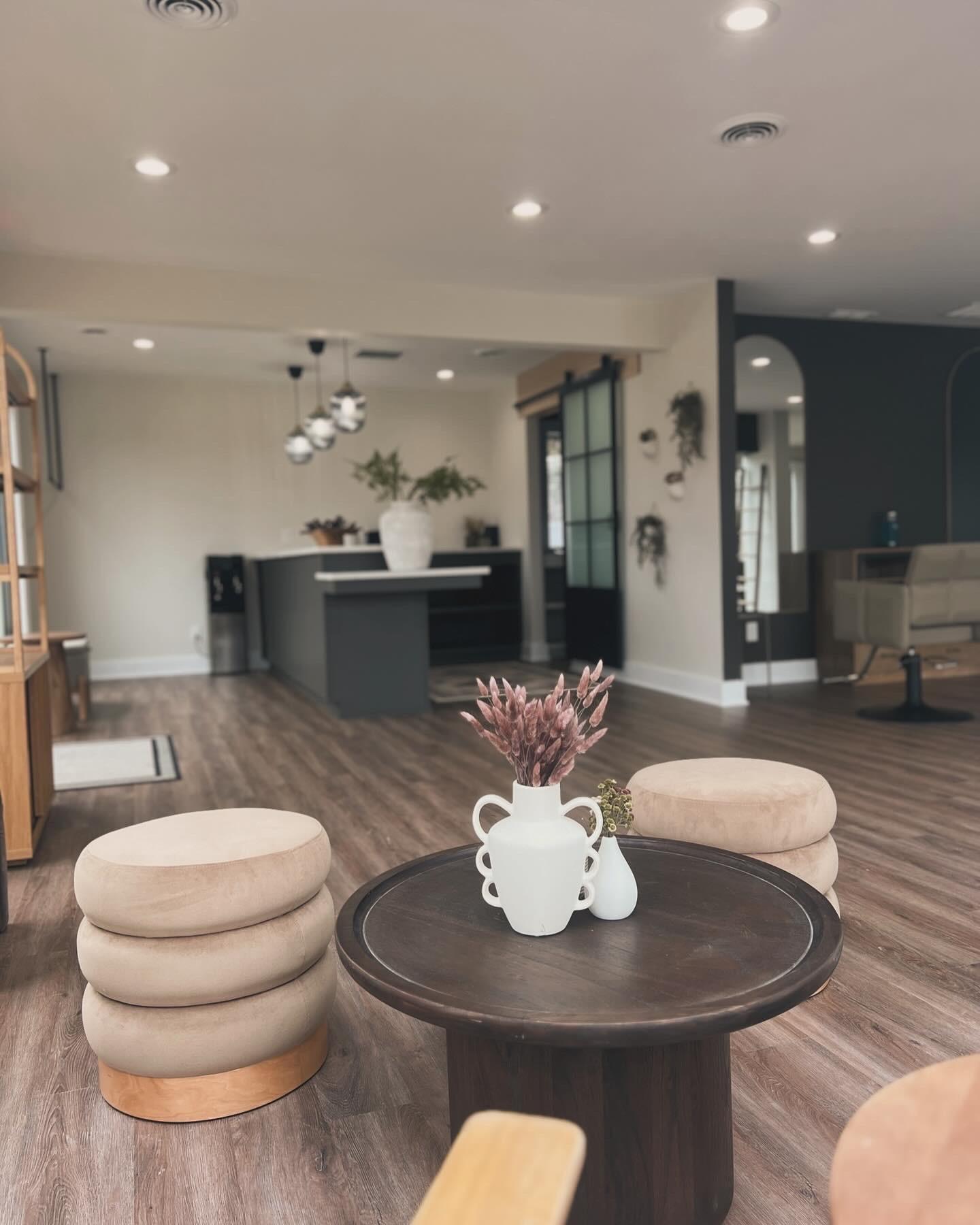 The rooted. salon lounge — wash stations framed by natural greenery and warm neutral tones